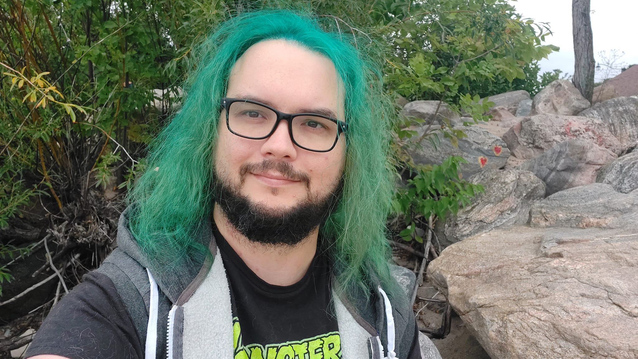 A man with green hair stands outside at a boulder breakwater, photo 11